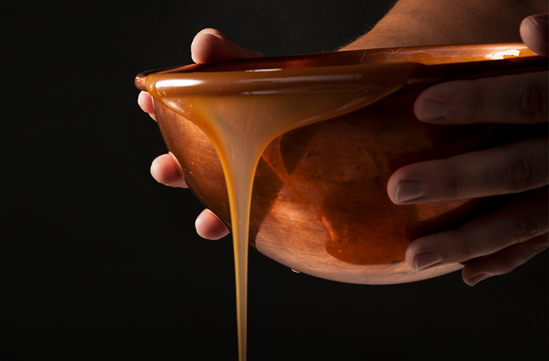 Copper bowl pouring melted chocolate, representing Russell Stover's heritage of fine chocolate making in copper kettles